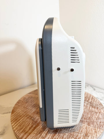 A Sonoscape ultrasound machine shown from a side angle, resting on a round wooden board against a plain off-white background.