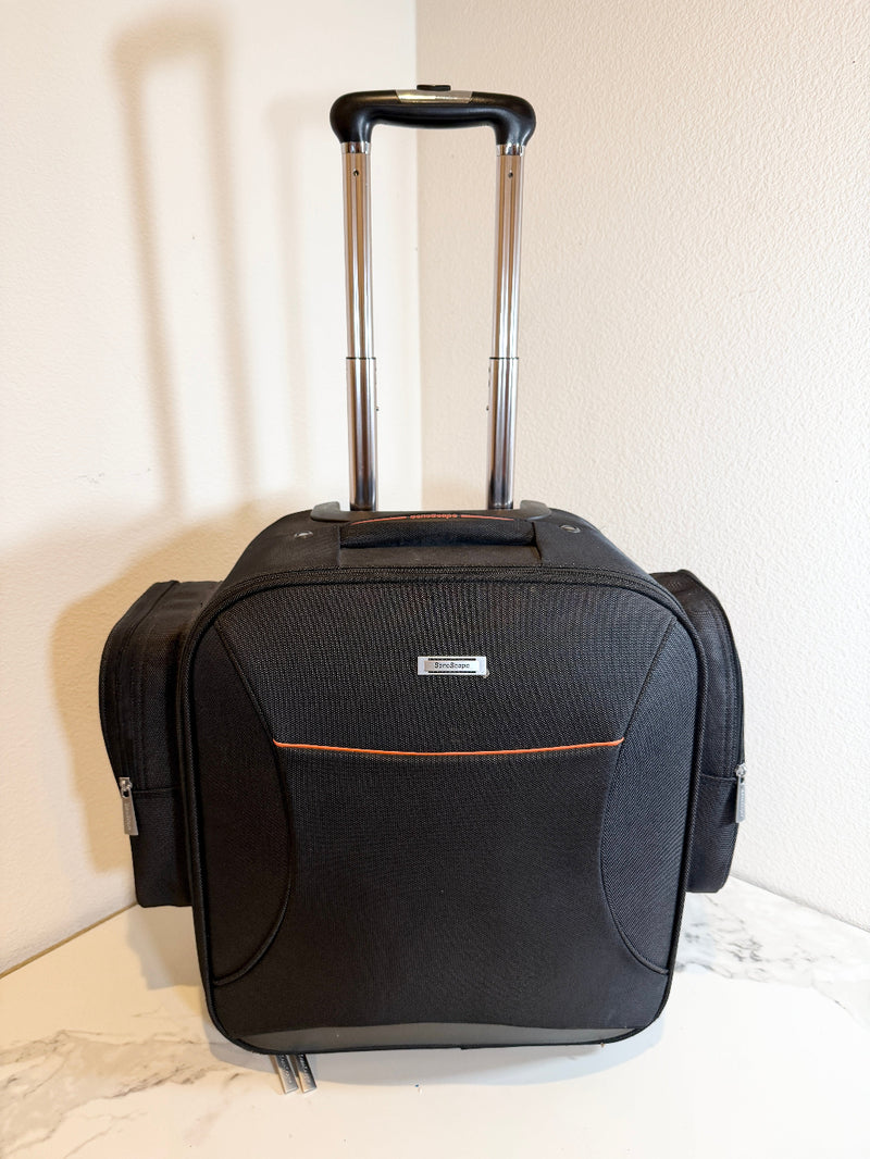 Sonoscape rolling bag with an extended handle, standing upright on a light marble-like surface against a textured off-white wall. The bag features a front zippered pocket with a thin orange accent line and a small silver brand plaque.