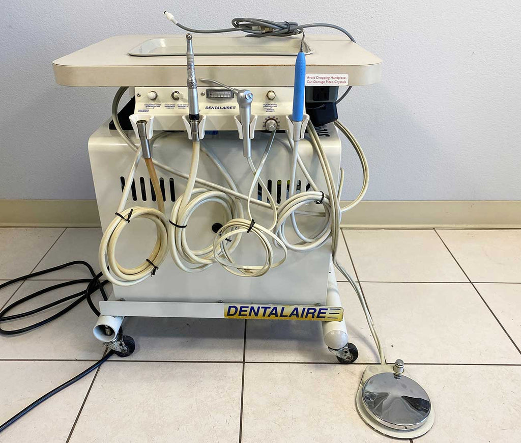 Front picture of the DentalAire Dental Machine with Air Compressor  with a foot pedal next to it 